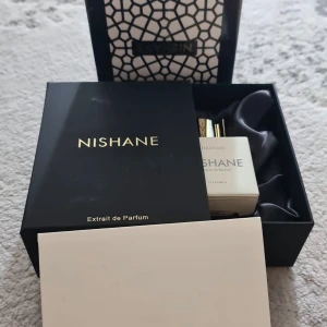 Nishane Hacivat Extrait de Parfum - Lyxig parfym från Nishane, Hacivat Extrait de Parfum, i elegant vit flaska med gulddetaljer. Kommer i exklusiv svart presentask med guldtext och mönstrad ytterkartong..