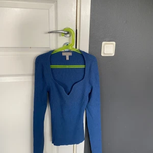 Blå ribbad tröja från H&M - Säljer en blå ribbad långärmad tröja från H&M i storlek XS. Tröjan har djup v-ringning och är figurnära i modellen. Perfekt för dig som gillar en enkel men snygg stil.