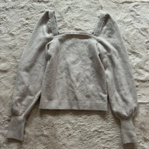  Stickad tröja med puffärmar - Superfin ljusgrå/beige stickad tröja från H&M med fyrkantig urringning och puffiga långärmar. Tröjan har breda muddar vid ärmslut och nederkant. Storlek S