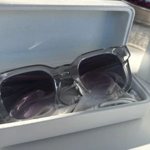 Solglasögon från CHIMI - Säljer ett par snygga solglasögon från CHIMI med transparent båge och mörka glas. Modell 04 Grey. Kommer med originalfodral, putsduk och påse. Helt nya och kvitto finns kvar!
