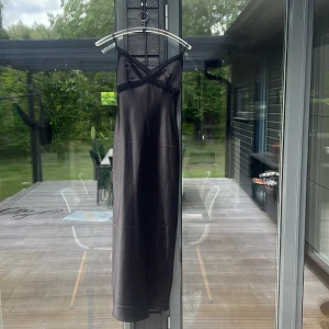 Svart långklänning i satin från Gina Tricot - Supersnygg svart långklänning från Gina Tricot i satinliknande material. Klänningen har tunna axelband, v-ringning och spetsdetaljer vid bysten. Perfekt för dig som vill ha en elegant och stilren look. Nypris 599kr Använd en gång. 