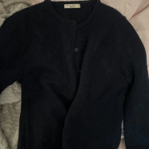 Mörk blå kofta - Mysig mörk blå kofta från Gina Tricot med rund halsringning och knäppning framtill. Tröjan har lång ärm och är tillverkad i ett fluffigt, mjukt material som känns lyxigt och varmt.