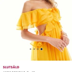 Gul maxiklänning med volang från ASOS DESIGN - Superfin gul maxiklänning med bara axlar och volangdetaljer. Klänningen har offshoulder-modell och är lång med ett luftigt, flowy tyg. Perfekt för dig som vill sticka ut med färg och stil.
