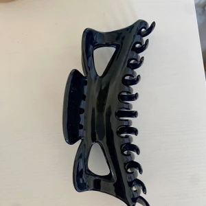 Stor svart hårklämma  - En väldigt stor svart hårklämma som är perfekt för dig som har långt och tjockt hår och vill kunna sätta upp hela håret utan att allt ramlar ner. Den har bra grepp och är i väldigt bra skick.