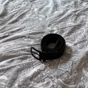 Svart flätat bälte med metallspänne - Säljer ett svart flätat bälte med stilrent svart metallspänne och detaljer i svart skinn.  105cm men bältet har en flexibel design som gör det enkelt att justera längden. 