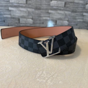 Snygg L*V bälte - Bältet är helt ny och är aldrig använt. Den har en silver logo och svart och grå läder. Bältet är såklart ett läderbälte. Den är size 105