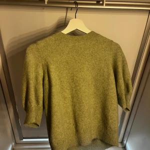 Grön stickad tröja med puffärm - Säljer en ljusgrön stickad tröja med puffärmar och ribbade muddar. Tröjan har rund halsringning och är perfekt för kyligare dagar. Supermjuk och skön att ha på sig.