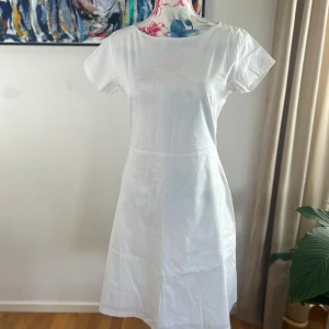 Vit klänning från Cissi och Selma - Säljer en klassisk vit klänning från Cissi och Selma. Klänningen har rund halsringning, korta ärmar och dragkedja i ryggen. Den är sydd i ett mjukt bomullstyg och har en lätt utställd passform som ger en tidlös look. Saknar storleksetikett men upplevs som 36/38.