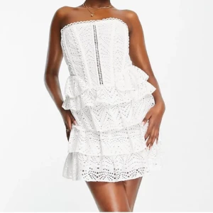 Vit axelbandslös volangklänning - Vit axelbandslös klänning med volanger och broderade spetsdetaljer. Klänningen har gummi vid brösten så att den inte glider ner och formar midjan superfint! Perfekt inför studenten, midsommar etc!!  Kan mötas i stockholm/ posta snabbt! 