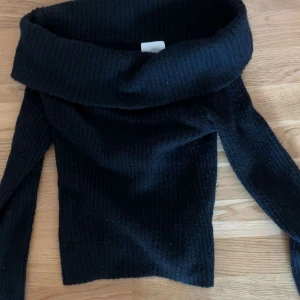 Svart ribbad offshoulder stickad tröja - Säljer en svart stickad tröja med bred offshoulder i XS. Använd några gånger men kommer inte längre till användning.