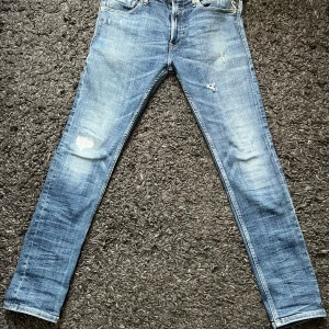 Replay Jondrill slim jeans blå - Snygga Replay Jondrill jeans i ljusblå tvätt med slitningar och slim passform. Klassisk femficksmodell med Replay-logga på fickan och läderpatch bak. Jeansen är i stretchig bomull och har dragkedjegylf. Perfekta för en avslappnad och trendig look. Pris kan diskuteras vid snabb affär