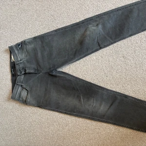 Replay grå tapered jeans Sandot 29 - Snygga grå jeans från Replay i modellen Sandot med relaxed tapered passform. Jeansen har klassisk femficksdesign, svarta detaljer och diskret Replay-logga på bakfickan. 