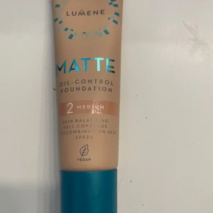 Lumene Matte Oil-Control Foundation - Matt foundation i nyansen 2 Medium från Lumene. Ger full täckning och balanserar huden med oljekontroll, perfekt för blandhy eller fet hy. Innehåller SPF20 och är vegansk. Kommer i en beige tub med blått lock, 30 ml.