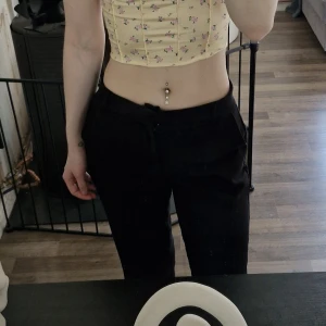 Svarta kostymbyxor med normal passform - Säljer ett par svarta kostymbyxor med normal passform och raka ben. Byxorna har hällor för bälte, diskreta fickor i sidorna och klassisk stängning framtill. Slits längst ner på benen. Perfekta för en stilren och enkel look. Lite korta för mig som är 176 cm lång. Noppror finns.