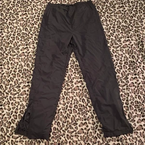 Mörkgrå träningsbyxor  - Snygga mörkgrå träningsbyxor från Lotto med elastisk midja och dragsko. Byxorna har dragkedjor vid bensluten för enkel på- och avtagning. Skulle säga storlek M.