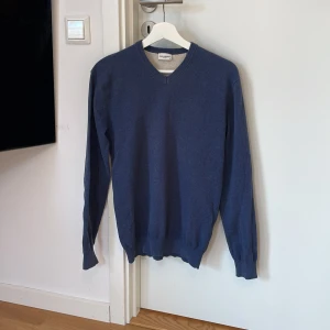 Mörkblå tröja från John Henric - Säljer en stilren mörkblå tröja från John Henric. Tröjan har en v-ringad hals och långa ärmar, perfekt för en klassisk look. Tillverkad i ett mjukt material som ger en bekväm passform. Passar utmärkt till både vardag och mer uppklädda tillfällen.