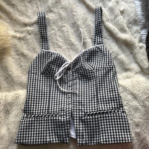 Svartvit rutig korsettopp - Snygg svartvit rutig korsettopp med knytning framtill. Toppen har breda axelband