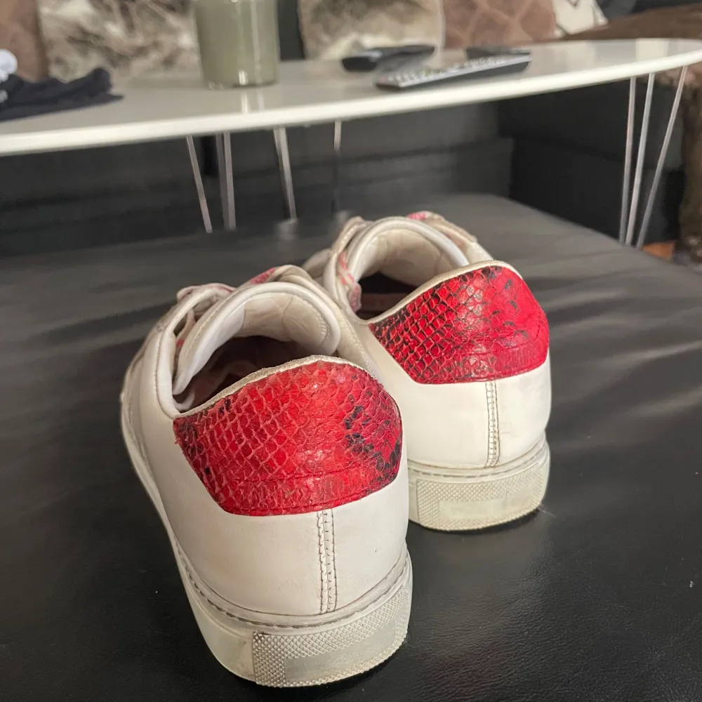 Snygga vita sneakers från Zadig & Voltaire med röda detaljer och snörning. Skorna har en unik design med röd ormskinnsmönstrad häl och rosa snören med logotyp. Perfekta för en trendig look. Använda men bra skick, lite repor vid framsidan❤️. Kengät.