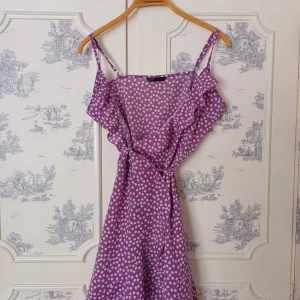 Lila prickig klänning från Shein - Säljer en söt lila klänning från Shein med vita prickar och volangdetaljer. Klänningen har smala axelband och ett knytband i midjan för en fin passform. Perfekt för sommarens alla tillfällen! 💜 lite svår fotad då man ska knyta den runt sig 