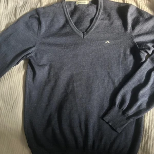 Blå tröja från J.Lindeberg - Säljer en stilren blå tröja från J.Lindeberg med v-ringning. Tröjan har ett litet hål som inte märks av när den är på. Som vanligt, priset är inte hugget i sten och kontakta vid funderingar!🎉