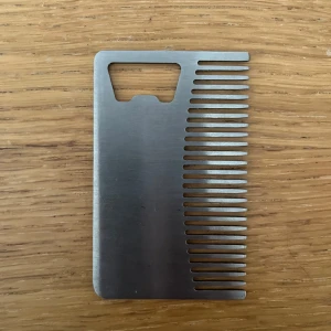Hårkam plus kappsylöppnare   - Perfekt för dig som är på språng! Med denna smidiga kam i plånboksformat fixar du frisyren på nolltid. Och när det är dags för fest? Då plockar du fram kapsylöppnaren och smäller upp en kall öl.