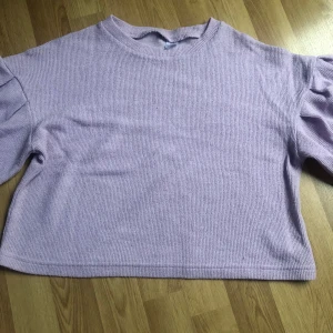 Ljuslila stickad tröja - Säljer en söt ljuslila stickad tröja med puffiga långa ärmar. Perfekt för en mysig dag. Tröjan har en rund halsringning och en avslappnad passform. Passar bra till både jeans och kjol. 💜