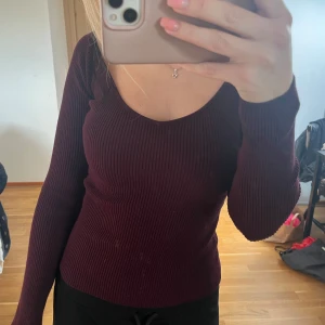 Vinröd ribbad tröja - Säljer en vinröd ribbad tröja med v-ringning. Tröjan har långa ärmar och en tight passform nypris 199