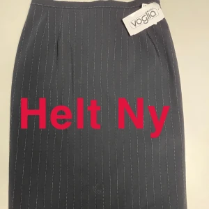 Randig kjol från Voglia - Helt ny randig kjol från Voglia i mörk färg med ränder. Orginalpris 795:-. Kjolen har en slits baktill och en klassisk passform. 