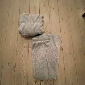 Grå hoodie och byxor set - Mysigt grått set med hoodie och byxor. Hoodien har dragkedja och fickor framtill, medan byxorna har en bekväm dragsko i midjan och fickor både fram och bak. Perfekt för en avslappnad dag hemma eller ute. I storlek 8-9 år men känns större och är större, ny pris 1700 men säljer för 900kr skriv för fler bilder eller frågor.
