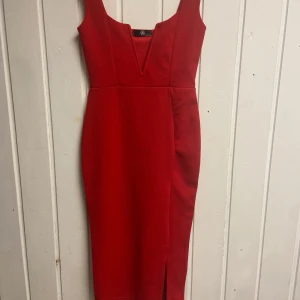 Röd klänning med slits - Snygg röd klänning med en djup v-ringning och slits framtill, klänningen har en figurnära passform som framhäver silhuetten.❤️