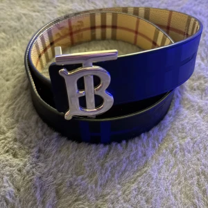 Burberry skärp - Snyggt bälte där man kan ändra sida från svart till det klassiska burberry mönstret. Perfekt för att ge en stilren touch till din outfit.