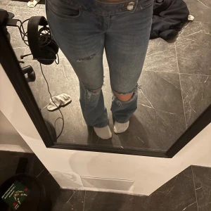 Blå jeans med slitningar - Snygga blå jeans med slitningar på knäna. Passar perfekt på mig som är 162cm, och byxorna är lite lågmidjade. Tryck på köp nu!