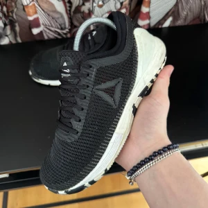 Svarta sneakers från Reebok - Snygga svarta sneakers från Reebok med vit sula och nätmaterial för bra ventilation. Skorna har en diskret logga på sidan och snörning framtill. Perfekta för träning eller en aktiv vardag.