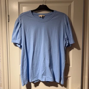 Ljusblå t-shirt från Pernilla Wahlgren kollektionen - Säljer en enkel och stilren ljusblå t-shirt. Perfekt för en avslappnad look. T-shirten har en rund hals och korta ärmar. Passar bra till jeans eller shorts för en casual stil. Endast tvättad en gång och provad ej använd då jag inte känner att färgen passar mig. 
