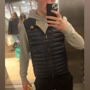 Mörkblå dunväst från Parajumpers - Säljer en snygg mörkblå dunväst från Parajumpers som är perfekt nu för våren och sommaren, jag säljer eftersom den börjar bli för liten. Västen har ett jättelitet hål bakom höger ficka som man ej kan se när den används och den är enkel att matcha kläder med. Skriv om du är intresserad! Det