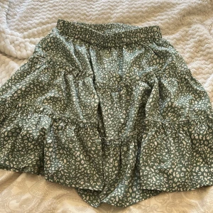 Grön leopardmönstrad kjol från SHEIN - Snygg grön kjol med leopardmönster från SHEIN. Kjolen har en elastisk midja och volanger som ger en fin rörelse. Perfekt för en trendig look!