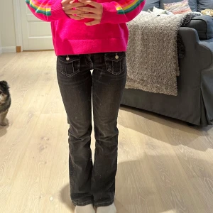 Svarta jeans med vita sömmar - Snygga svarta jeans med vita sömmar och dekorativa fickor. Byxorna har en lågmidjad passform och en bootcut-stil som ger en klassisk look. Perfekta för en avslappnad stil.