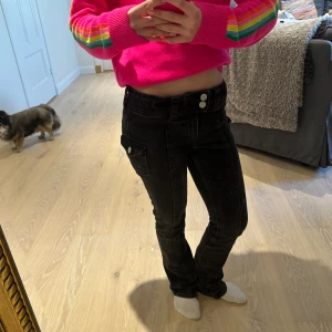 Svarta jeans med knappar - Snygga svarta jeans med tight passform och låg midja. De har dekorativa knappar och en klassisk femficksdesign. Perfekta för en stilren look. De är lite trasiga vid insidan av jeansen där man spänner åt! Byxorna är från hm och säljs inte längre!