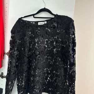 Svart spetsblus från Kappahl - Säljer en elegant svart spetsblus från Kappahl. Blusen har ett vackert blommigt spetsmönster och långa ärmar. Perfekt för att lägga till en touch av elegans till din garderob. Passar bra till både jeans och kjol.