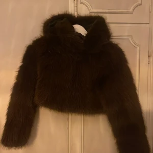 Brun croppad pälsjacka - Jag säljer en snygg brun croppad pälsjacka med långärmad design. Jackan har en fluffig känsla, och funkar perfekt nu inför våren. Säljer den pågrund av att jag fick hem fel storlek och har ingen möjlighet att retunera den. (Aldrig använd) pris kan abolsut diskuteras