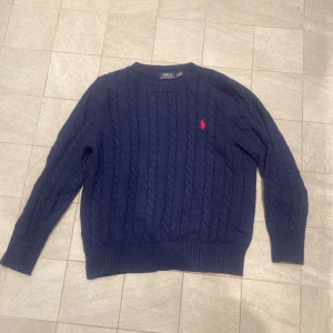Mörkblå cable knit från Polo Ralph Lauren - Asfet cable knit från Polo Ralph Lauren, Storlek L i ungdom så den passar Xs och kanske S, lite liten på mig som är 178. Annars är den använd och lite nopprig men absolut inget överdrivet. Vid fler frågor eller funderingar är det bara att skicka iväg ett meddelande!