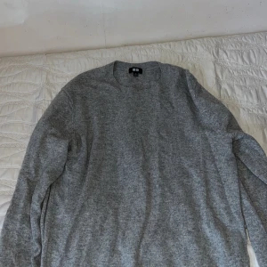 Grå tröja från Uniqlo cashmere tröja  - Säljer en stilren grå tröja från Uniqlo. Perfekt för kyligare dagar med sin mjuka och bekväma passform. Tröjan har långa ärmar och en klassisk rund halsringning.
