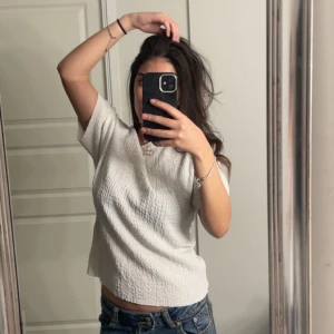 Vit offshoulder topp - Säljer en stilren vit offshoulder topp med korta ärmar. Toppen har en texturerad yta som ger en unik look. Perfekt för en avslappnad stil.