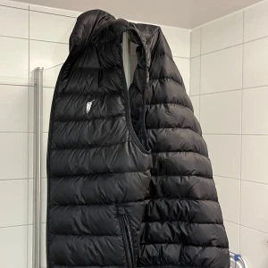 Svart dunväst från Polo Sport - Säljer en snygg dunväst i svart färg. Den är i gott skick. Köpt från Pandabuy därför säljs den för det låga priset. Storlek S. Pris kan diskuteras. Står inte för frakt.
