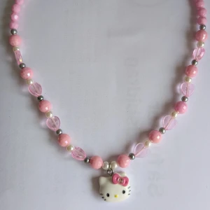Rosa halsband med Hello Kitty-berlock - Charmigt halsband med rosa och vita pärlor samt en söt Hello Kitty-berlock. Perfekt för att lägga till en lekfull touch till din stil. Passar barn