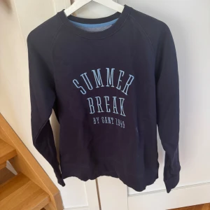 Mörkblå sweatshirt från GANT - Säljer en snygg mörkblå sweatshirt från GANT med texten 'Summer Break' tryckt på framsidan. Tröjan har långa ärmar och en rund halsringning. Bra skick. Perfekt för en avslappnad stil. Storlek:176. Nypris:599kr. Säljer 349kr