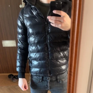 Svart pufferjacka med dragkedja - Säljer en svart peak performance pufferjacka. Storlek 170 passar som en xs för vuxen storlek. Skitbra jacka som håller en varm har ett litet hål kolla andra bilden. Öppen för prisförslag så bara skicka!