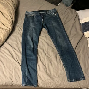Blå jeans från Replay - Säljer ett par snygga blå jeans från Replay med klassisk femficksdesign. Jeansen har en normal passform och är perfekta för en avslappnad stil. Märkesdetaljer syns på bakfickan och insidan av linningen.