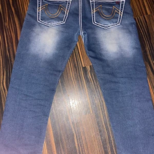 Feta blåa OG true religion jeans - Säljer ett par blåa jeans från True Religion med big-t stitches. Jeansen har en snygg tvättad look. Perfekta för en calm luh fit. Pröjsa jätte gärna vill få byxorna sålda så snabbt som möjligt.