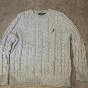  Kabelstickad Polo Ralph Lauren - Säljer en klassisk ljusgrå kabelstickad tröja från Polo Ralph Lauren. Den sitter som en M/S. Ställ frågor vid funderingar
